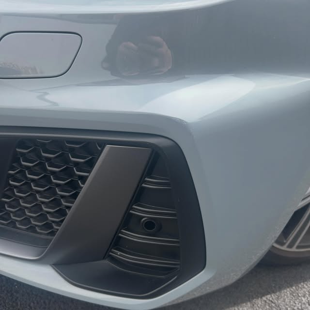Close view of a grey front bumper corner with a smooth painted edge beside the lower grille.